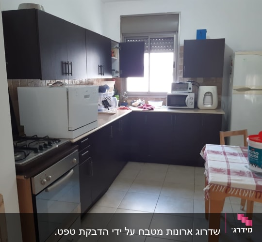 דלי צבע על שולחן במטבח עם ארונות כהים